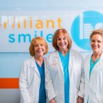 3 Doctor's smiling in front of their dental practice